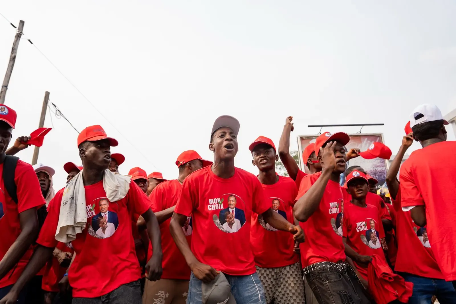 Jeunes militants en t-shirts rouges marchant et chantant dans la rue.